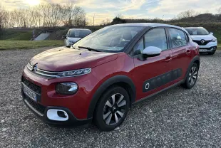 Citroën C3 rouge vue 3/4 avant droit, avec Airbump noir sur les portes et rétroviseurs blancs.