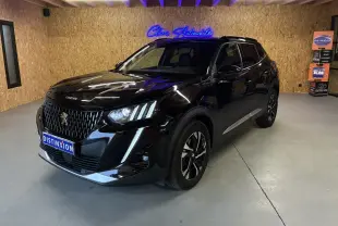 Peugeot 2008 noir 3/4 avant droit en intérieur, avec calandre distinctive et jantes bi-ton visibles.