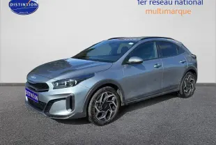 KIA Xceed gris en 3/4 avant droit, avec jantes alu au design hexagonal et calandre chromée visible.