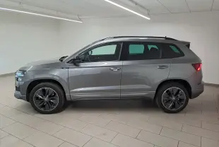 Vue latérale droite d'un Skoda Karoq 2.0 TDI 150 DSG7 Sportline gris graphite métallisé en intérieur, feux arrière allumés.