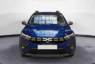 Vue frontale d'une Dacia Sandero Stepway TCE 90 bleu Iron avec calandre noire et détails bronze sur les rétroviseurs.