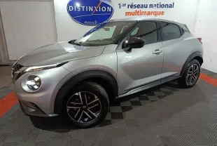 Vue 3/4 avant droite du Nissan Juke gris foncé 2025 avec jantes noires et phares LED allumés.