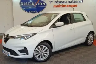 Renault ZOE Zen R135 blanc vue 3/4 avant droit, avec phares LED et jantes alliage en intérieur showroom.