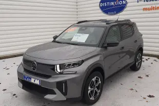 Vue 3/4 avant d'un Citroën C3 Aircross 2025 gris Mercury avec toit noir et jantes biton, stationné devant un mur blanc.