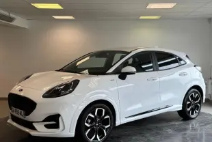 Ford Puma blanc glacier en 3/4 avant droit avec jantes alliage noires et toit noir dans un showroom intérieur.