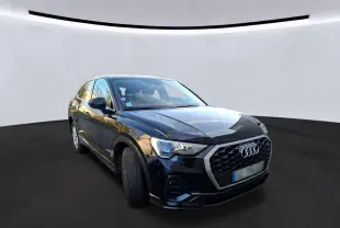 Audi Q3 Sportback noir vue 3/4 avant droit en intérieur, avec calandre hexagonale et jantes alu visibles.