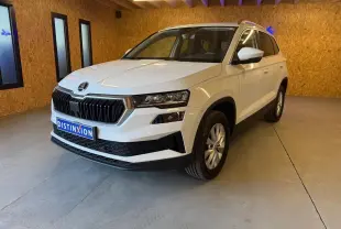 Vue 3/4 avant droite d'un Skoda Karoq blanc 2023 avec calandre noire et jantes alliage en intérieur.