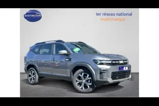 Vue 3/4 avant droite du Dacia Bigster gris métallisé avec barres de toit et jantes alliage distinctives.