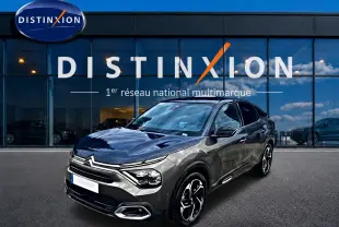 Citroën C4 2024 gris métallisé vue 3/4 avant avec jantes alu et calandre distinctive devant showroom Distinxion.