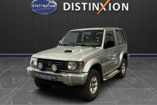 Mitsubishi Pajero Court gris aluminium vu en 3/4 avant droit, avec marchepieds et phares additionnels sur calandre.
