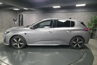 Peugeot 308 gris métallisé vue de profil côté gauche, avec jantes alliage noires et vitres surteintées.
