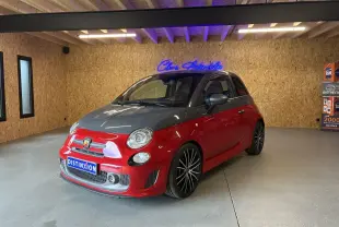 Vue 3/4 avant droite d'une Abarth 500 Competizione 2016 rouge et gris avec jantes noires en intérieur showroom.