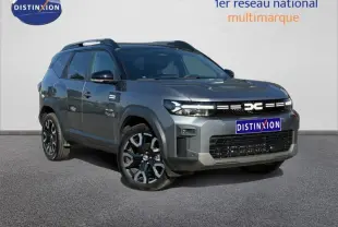 SUV Dacia Bigster gris schiste en 3/4 avant droit avec jantes alliage et barres de toit noires.