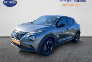 Nissan Juke Hybrid gris squale metal en 3/4 avant droit, avec jantes noires et détails noirs contrastants.