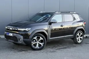 SUV Dacia Duster 2025 noir nacré en 3/4 avant droit, avec jantes alliage diamantées et barres de toit visibles.