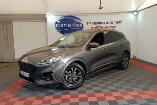 Ford Kuga gris foncé en 3/4 avant droit, avec jantes noires et calandre imposante dans un showroom.