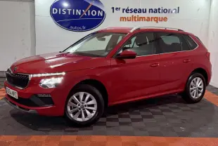 Vue latérale gauche d'un Skoda Kamiq rouge 2024 avec phares LED et jantes alliage en intérieur showroom.