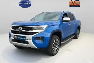 Vue 3/4 avant droite du Volkswagen Amarok bleu avec jantes alliage 21 pouces et marchepieds visibles.