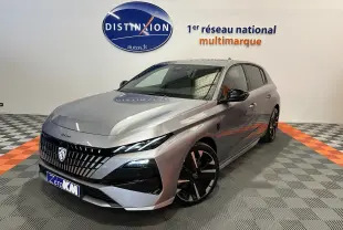 Peugeot 308 gris Artense vue 3/4 avant droit en showroom avec jantes noires et logo Distinxion en arrière-plan.