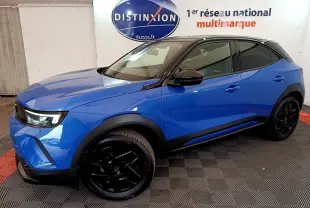 Vue 3/4 avant droite d’un Opel Mokka 2024 bleu avec toit noir et jantes noires dans un showroom.