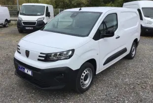 Peugeot Partner blanc en vue 3/4 avant droit, avec calandre noire et jantes acier, stationné sur un sol gravillonné.