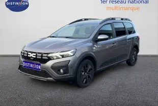 Dacia Jogger gris schiste métal en 3/4 avant droit, avec barres de toit et jantes noires distinctives.