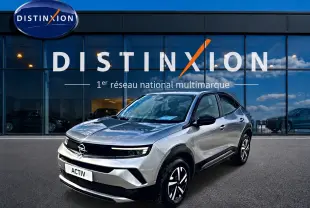 Opel Mokka gris en 3/4 avant droit, avec jantes noires et calandre noire brillante devant showroom Distinxion.