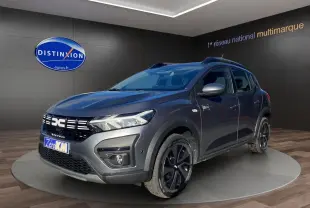 Vue 3/4 avant droite d'une Dacia Sandero Stepway gris schiste avec barres de toit et jantes noires.