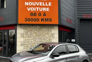 Peugeot 208 gris clair vue de profil droit devant un bâtiment avec panneau orange Distinxion.