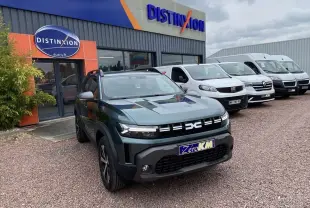 Dacia Duster 1.6 Hybrid 2025 vert INC en 3/4 avant droit, avec calandre moderne et plaques Zero KM visibles.