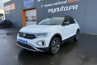 Volkswagen T-Roc blanc pur en 3/4 avant droit avec toit noir et jantes alliage 'Zürich' sur parking humide.