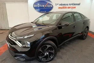 Citroën C4 X noir vue 3/4 avant droit, avec jantes noires et phares LED ellipsoïdaux visibles en intérieur showroom.