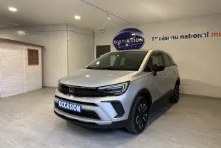Vue 3/4 avant droite d’un Opel Crossland gris 2023 en showroom avec jantes noires et plaque "OCCASION".