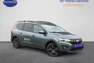 Dacia Jogger Vert Cèdre métallisé en vue 3/4 avant droit, avec barres de toit et vitres teintées.
