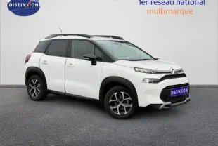 Vue 3/4 avant droit d'un Citroën C3 Aircross blanc Banquise avec barres de toit noires et jantes alliage.