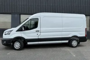 Vue de profil côté gauche d’un fourgon Ford Transit blanc avec bande noire basse et jantes tôles.