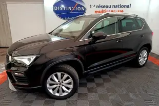 Vue 3/4 avant droite d'un SUV SEAT Ateca noir brillant, avec jantes alliage et barres de toit chromées en intérieur showroom.