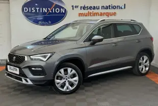 Vue 3/4 avant droit d'un SUV SEAT Ateca gris clair 2023 avec jantes alliage et barres de toit chromées.