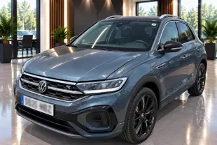 Volkswagen T-Roc 2025 gris métal en 3/4 avant droit avec jantes noires et détails R-Line visibles.