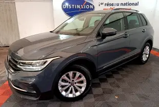 Volkswagen Tiguan gris clair vu en 3/4 avant droit dans un showroom avec jantes alliage et phares LED.