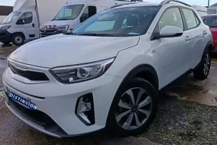 KIA Stonic blanc vue 3/4 avant droit, avec jantes alliage et calandre noire distinctive, en extérieur sur parking.