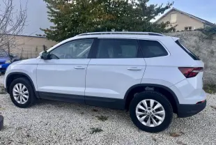 Vue de profil côté gauche d’un Skoda Karoq blanc 2024 garé sur un sol gravillonné avec jantes alliage.