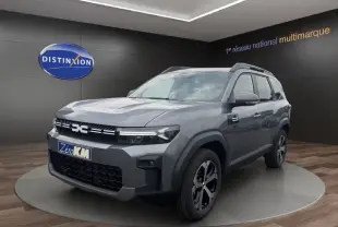Vue 3/4 avant du Dacia Bigster gris foncé, avec calandre noire distinctive et jantes bicolores modernes.