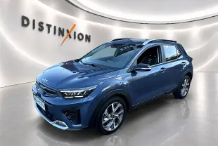 KIA Stonic gris en vue 3/4 avant droit, avec jantes alu et barres de toit visibles en showroom lumineux.