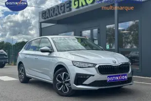Vue 3/4 avant droite d'une Skoda Scala gris argent métallisé avec calandre chromée et jantes alu devant un garage.