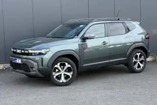 Vue 3/4 avant du Dacia Duster 2026 vert cèdre avec jantes alliage diamantées et barres de toit noires.