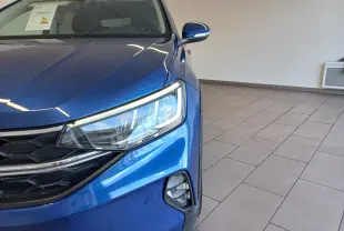 Vue de profil côté gauche d'un Volkswagen Taigo bleu récif avec jantes alliage 17 pouces dans un intérieur lumineux.