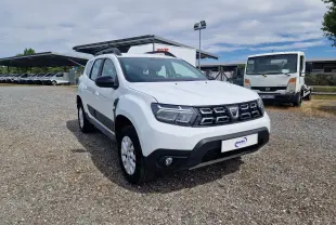 Dacia Duster blanc en 3/4 avant droit, SUV compact avec calandre noire et protections latérales noires.