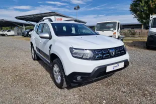 Dacia Duster blanc en 3/4 avant droit, avec calandre noire et protections noires sur les bas de caisse.