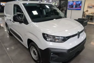 Citroën Berlingo Van blanc vue 3/4 avant droit en intérieur, avec pare-chocs noir et rétroviseurs noirs.